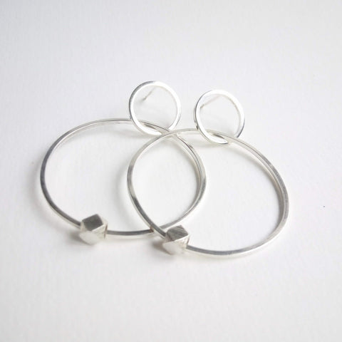 Silver square wire hoops with silver geo bead orbiting the large hoop. Earrings hang 5cm. Secured by stud and scroll.