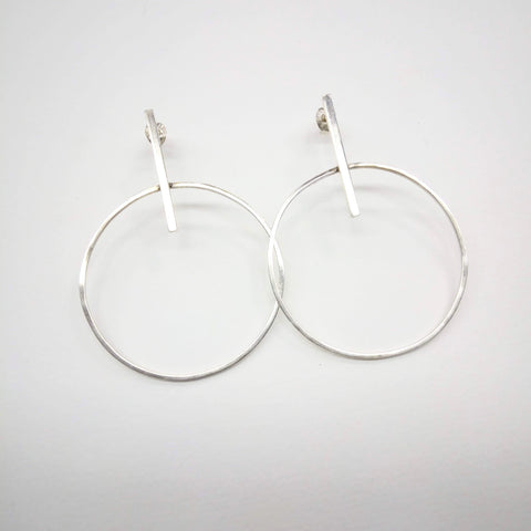 Square wire hoops fixed on a stick length with a stud setting. Hoops hang 5cm from the ear. Hoop is 3.5mm in diameter.