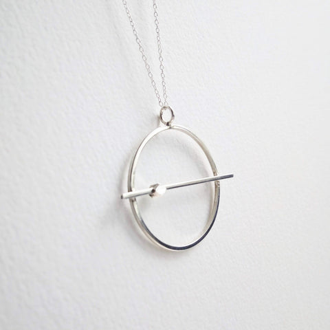 Planetary circle with a fine silver geometric bead sliding. Hangs from a fine sterling silver chain.